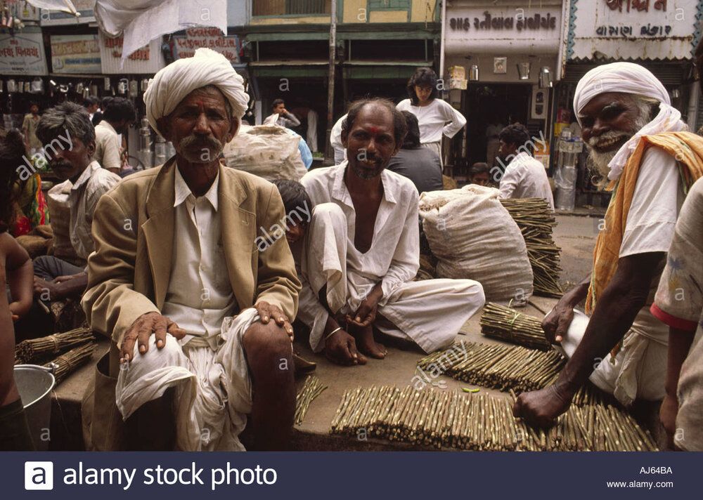 Group of indian men at stall selling local variant of toothbrushes AJ64BA