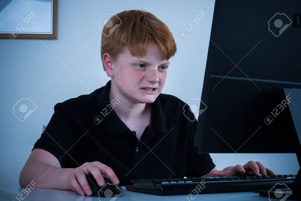 61867835 angry boy sitting on chair working on computer at home