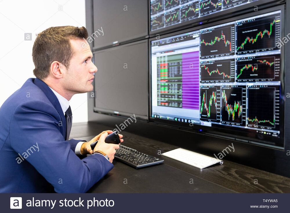 Stock broker trading online talking on mobile phone T4YWA5
