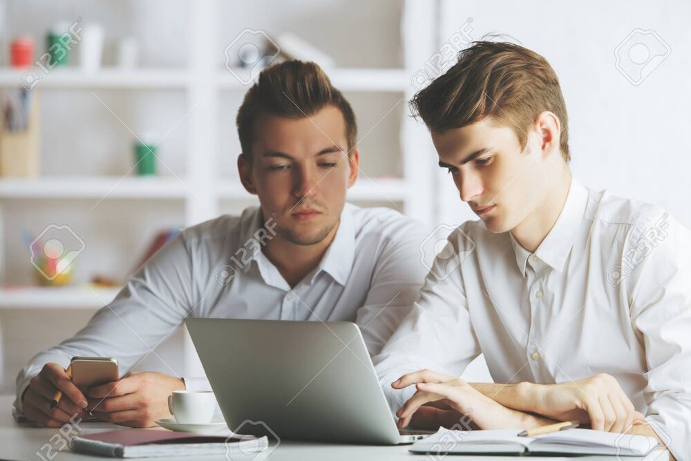 68522418 close up portrait of two attractive white men using mobile phone and working on proje