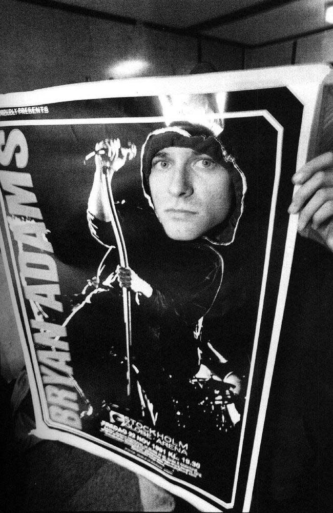 Kurt Cobain peeking through a Bryan Adams poster