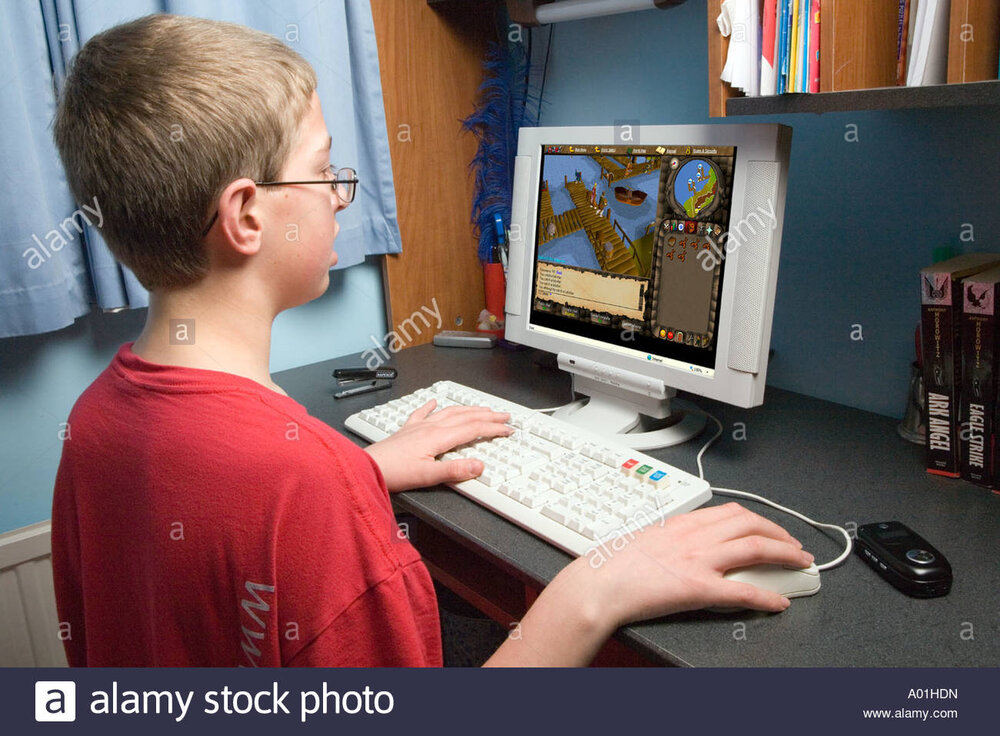 12 year old white boy playing runescape game on pc computer at home A01HDN