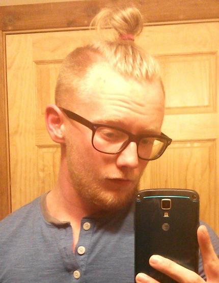 A picture of a blond guy with a man bun undercut hairstyle and glasses