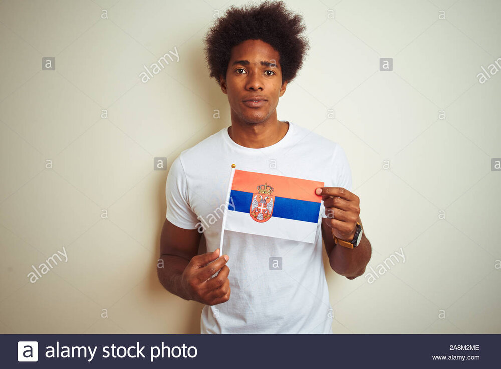 Young afro american man holding serbia serbian flag standing over isolated white background wi