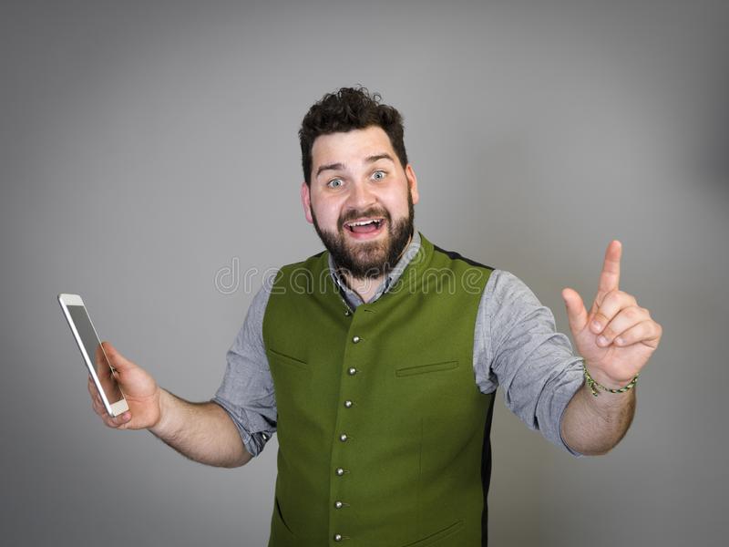 Young cool austrian man black hair beard traditional costume stands front grey background work