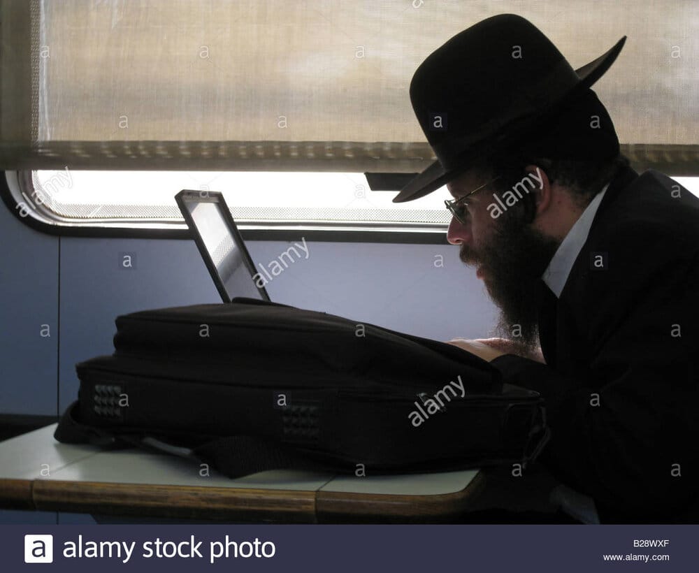 Ultra orthodox jewish passenger with laptop computer seated in train B28WXF
