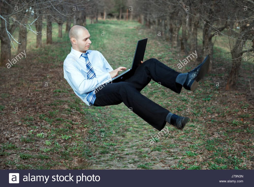 Man flying in the air in his hands he is holding a laptop J79N3N