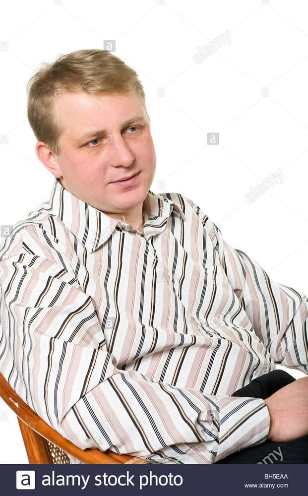 Portrait of middle age man who is sitting in armchair and looking BH5EAA