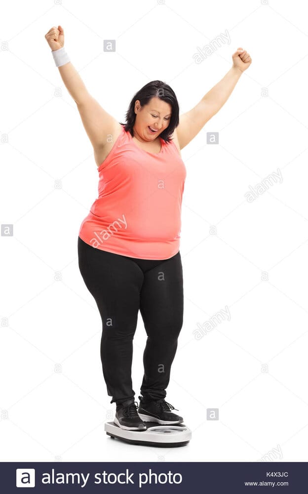 Full length portrait of an overweight woman standing on a weight scale K4X3JC