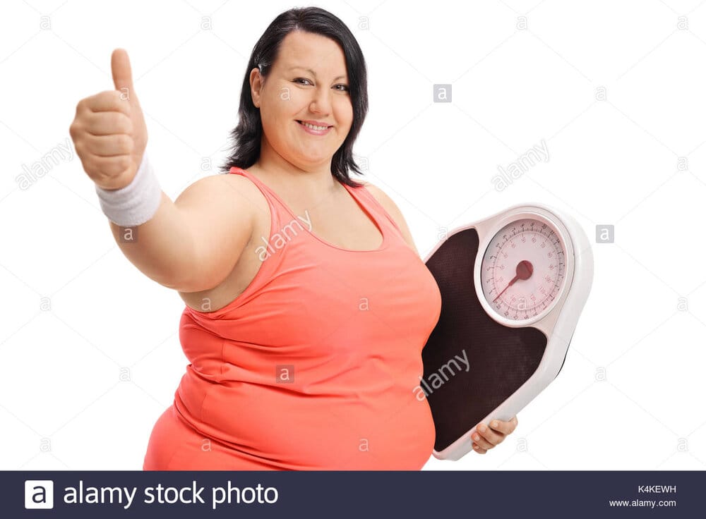 Overweight woman with a weight scale making a thumb up sign isolated K4KEWH