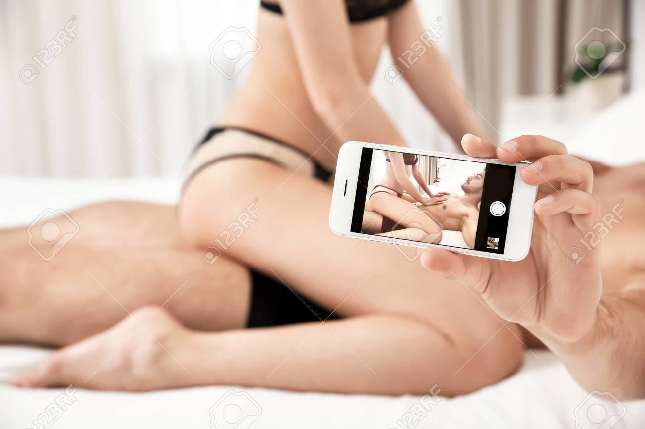 98353958 sexy young couple taking selfie in bedroom