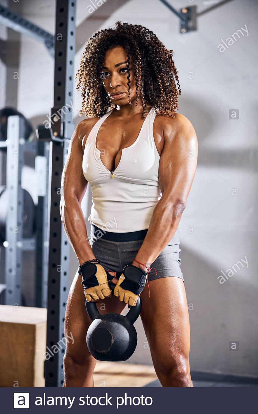Pensive female bodybuilder holding the weight piece 2DGK93F