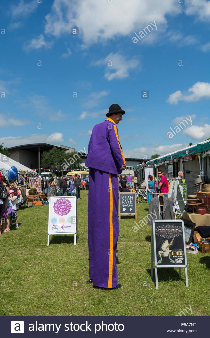 Man wearing purple suit on stilts at outdoor event in bakewell derbyshire E5A7NT