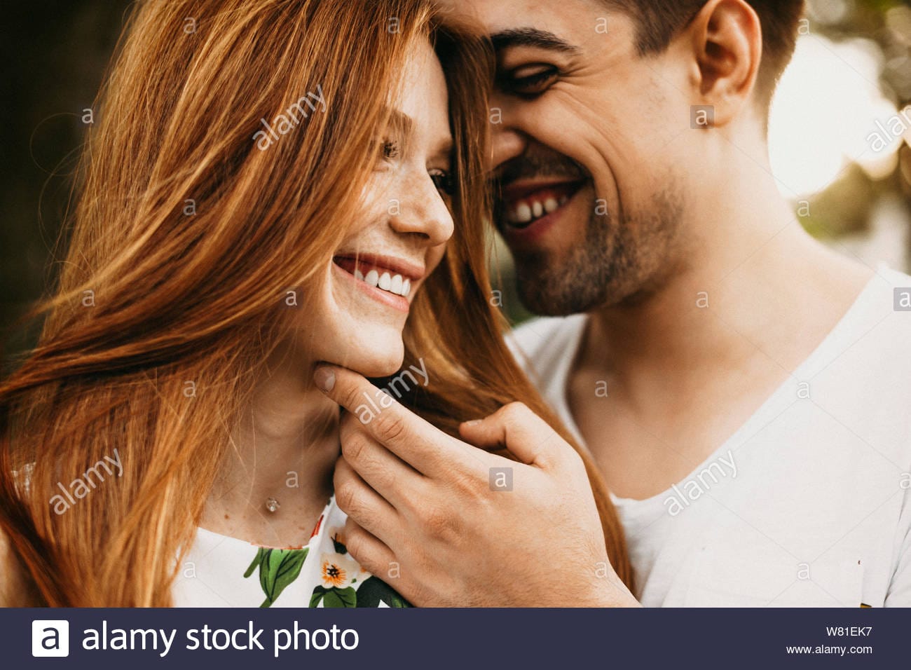 Close up portrait of a beautiful young caucasian couple having fun smiling while man is touchi