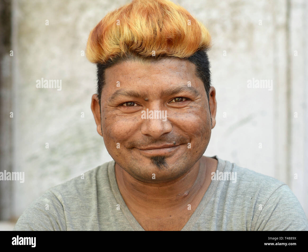 Young indian rajasthani man with golden blonde dyed hair and a soul patch poses for the camer