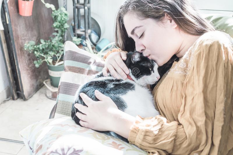 Girl resting armchair next to balcony kissing her black white cat selective focus soft focus g