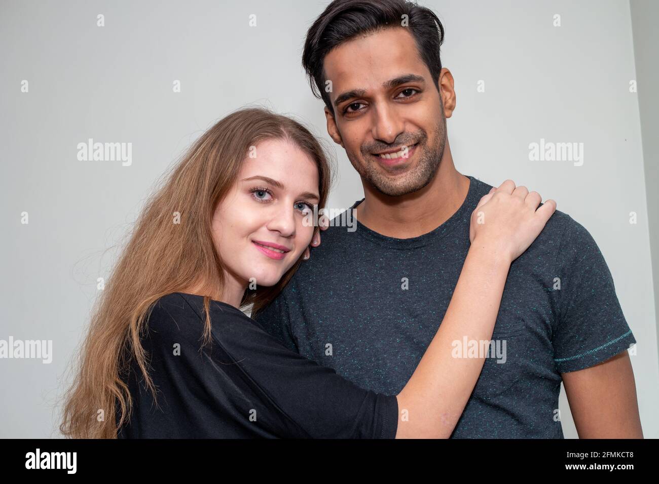 Indian asian man and russian white woman a harmonious young couple posing in the light backgro