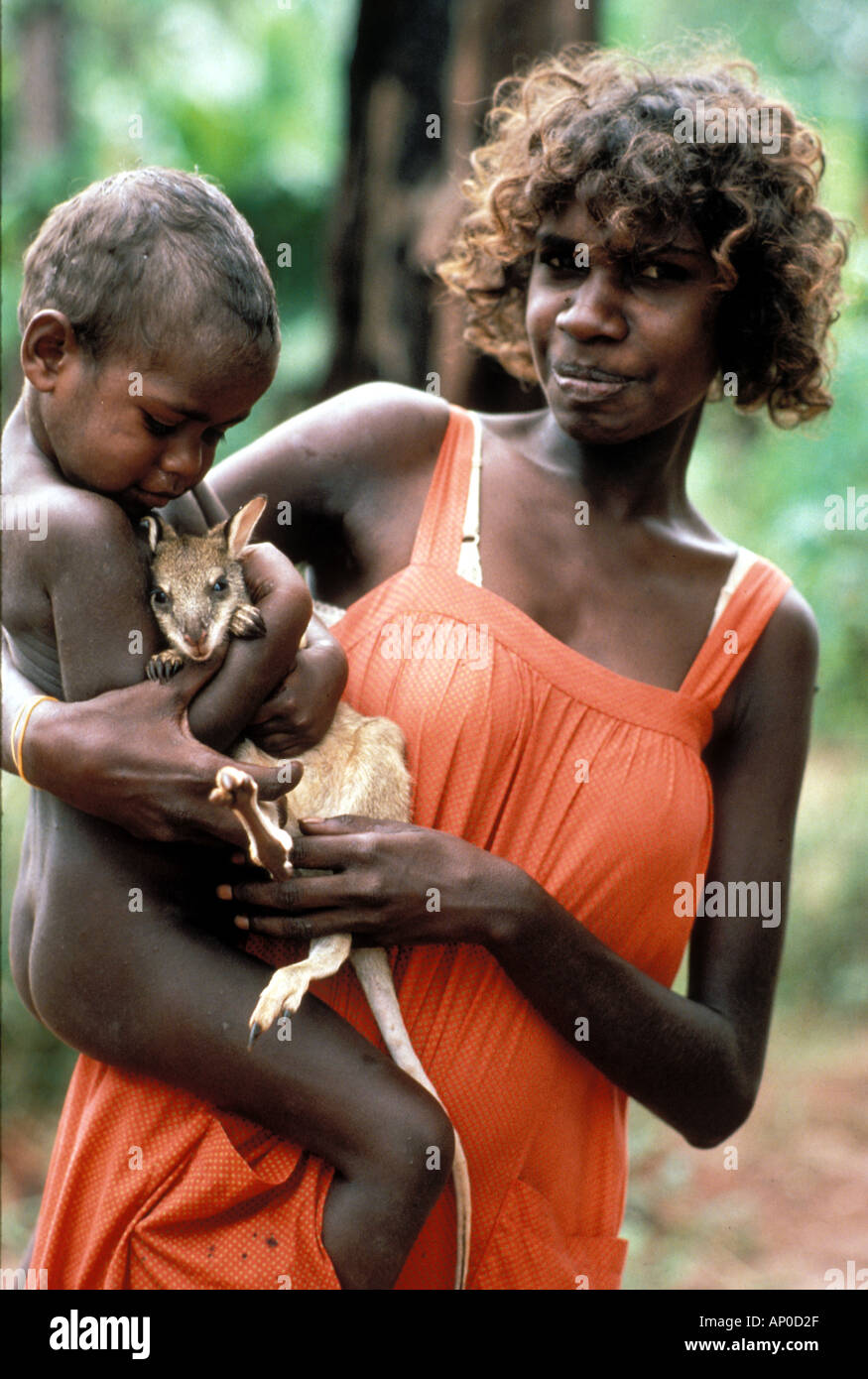 Aboriginal woman with her child cuddling pet baby kangaroo whose mother AP0D2F