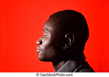 Portrait of a african man with eyes closed on red background stock photograph csp71564990