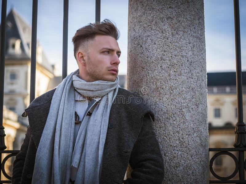 One handsome young man city setting urban european standing wearing black coat scarf winter da