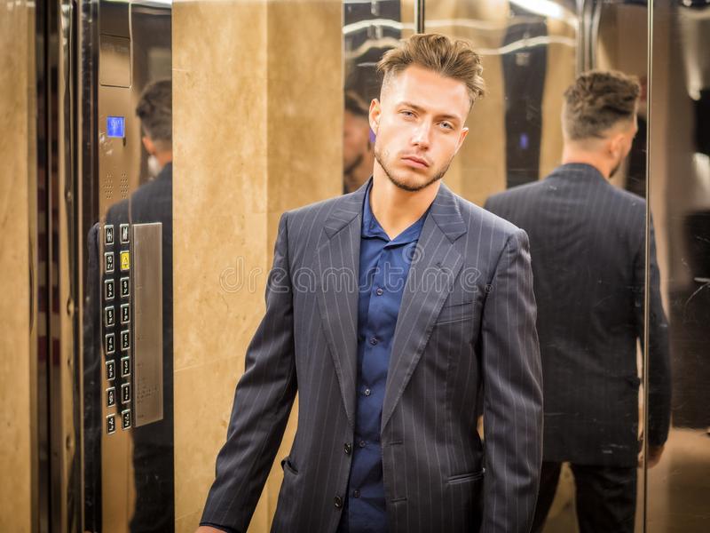 Handsome young man inside elevator looking camera business leaning against mirror lift 130493613