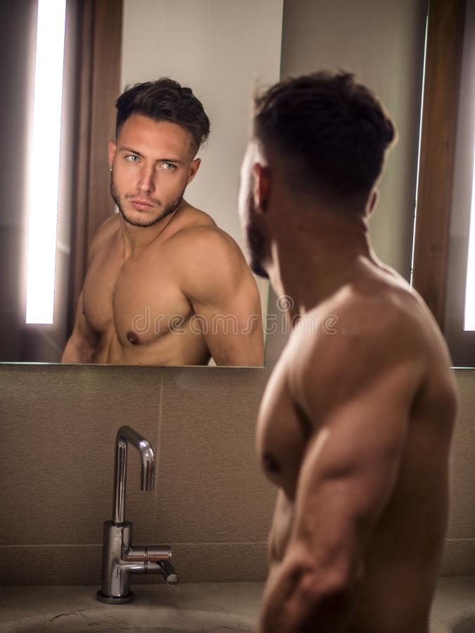 Shirtless handsome young man looking himself bathroom mirror morning sink 130493797