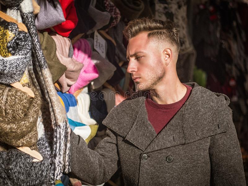 Young man browsing products open air market outdoor winter day looking hats scarves young man 