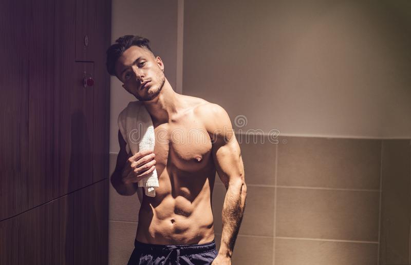 Shirtless muscular young male athlete gym dressing room changing towel shoulder shirtless youn