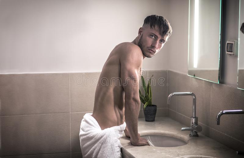 Shirtless young man bathroom looking camera sink mirror morning 135310453