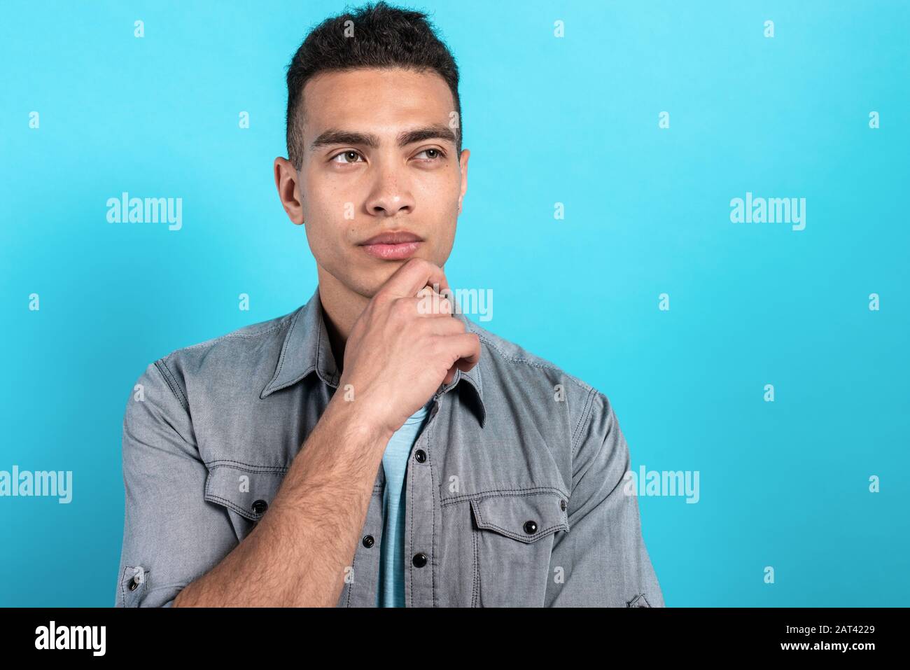 Handsome mulatto man looking dremly and touching his chin glance sideaway 2AT4229
