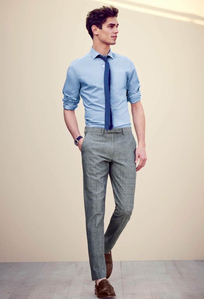 Twenty something man with pale blue shirt and rolled sleeves dark blue tie pale grey tweed tro