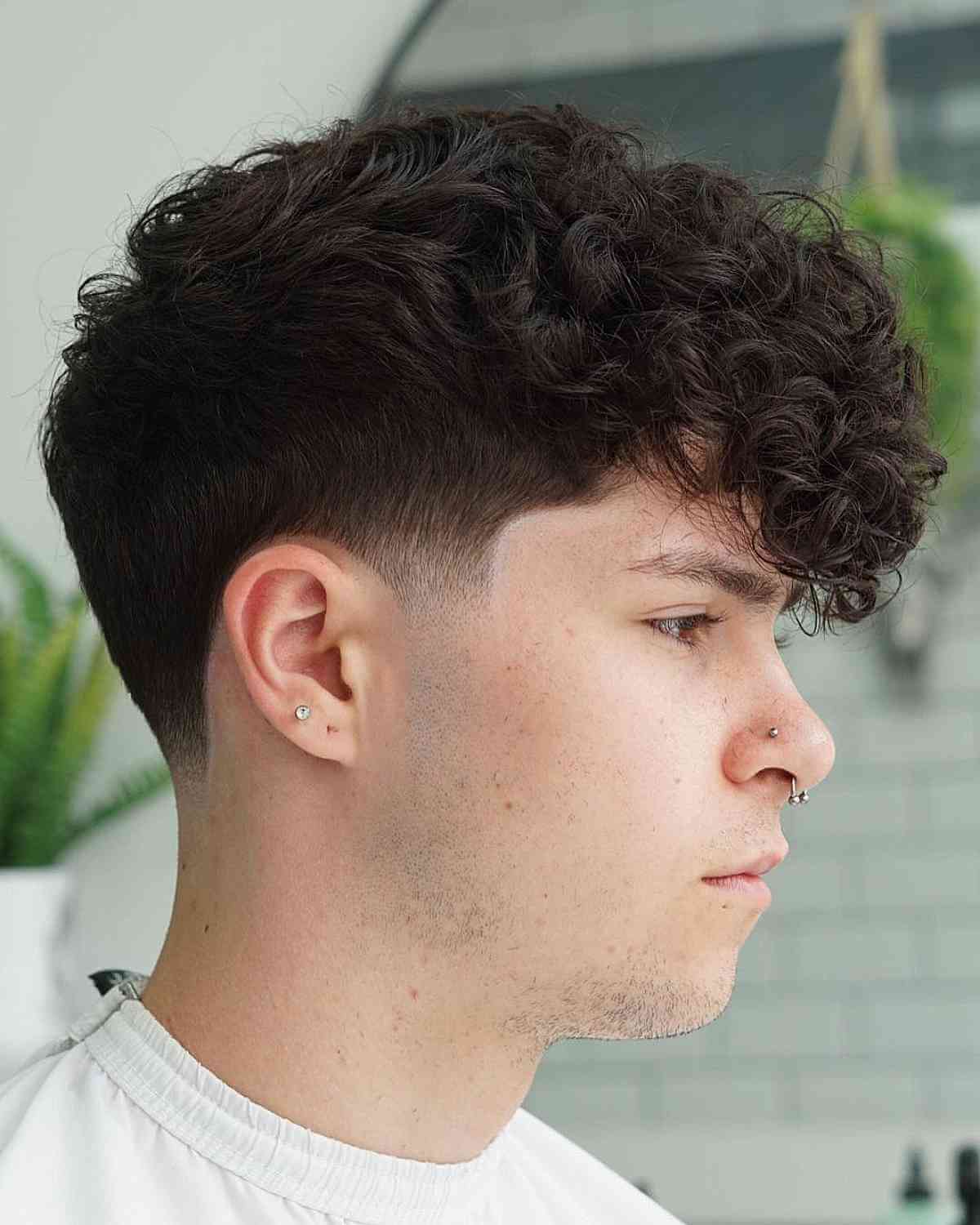 Low taper fade with loose curls on top for men