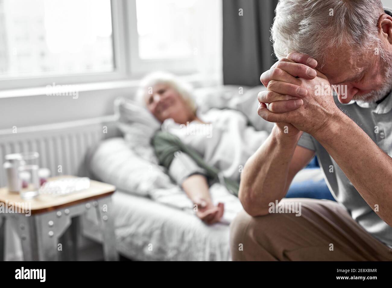 Elderly man crying and mourning the loss of his wife sitting by her side focus on upset man lo Elderly man crying and mourning the loss of his wife sitting by her side focus on upset man lo