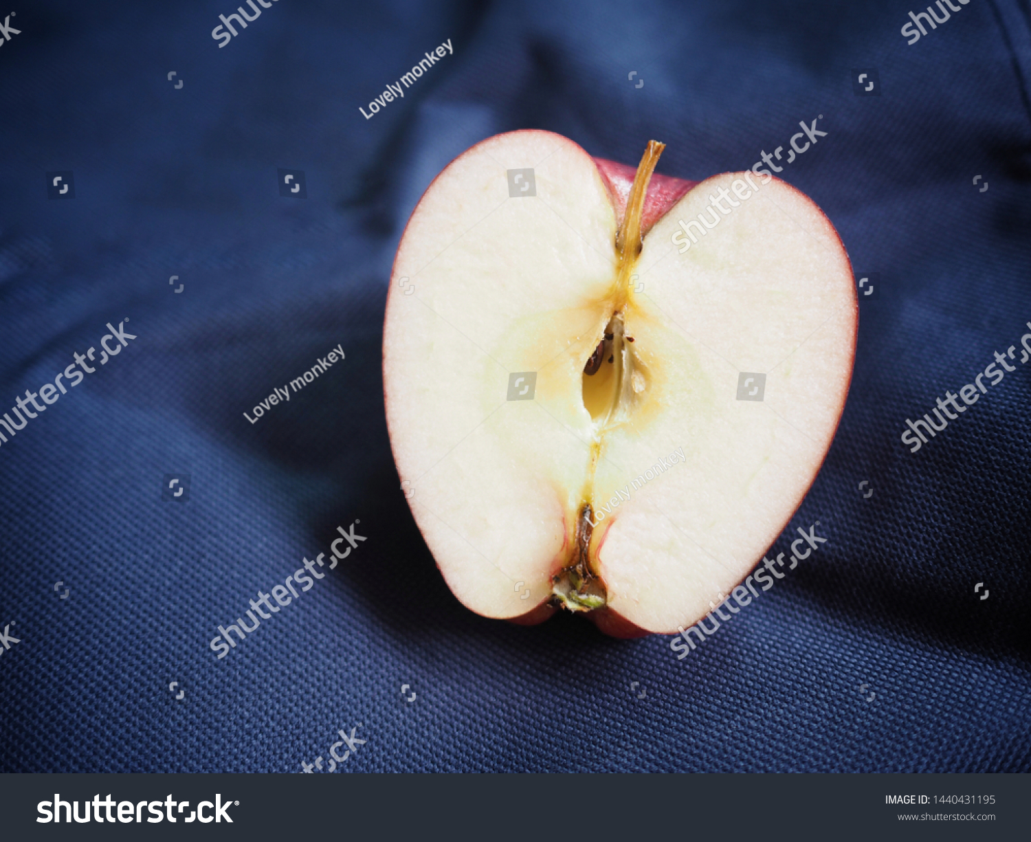 Stock photo close up of half piece red washington apple on dark blue background concept nutrit