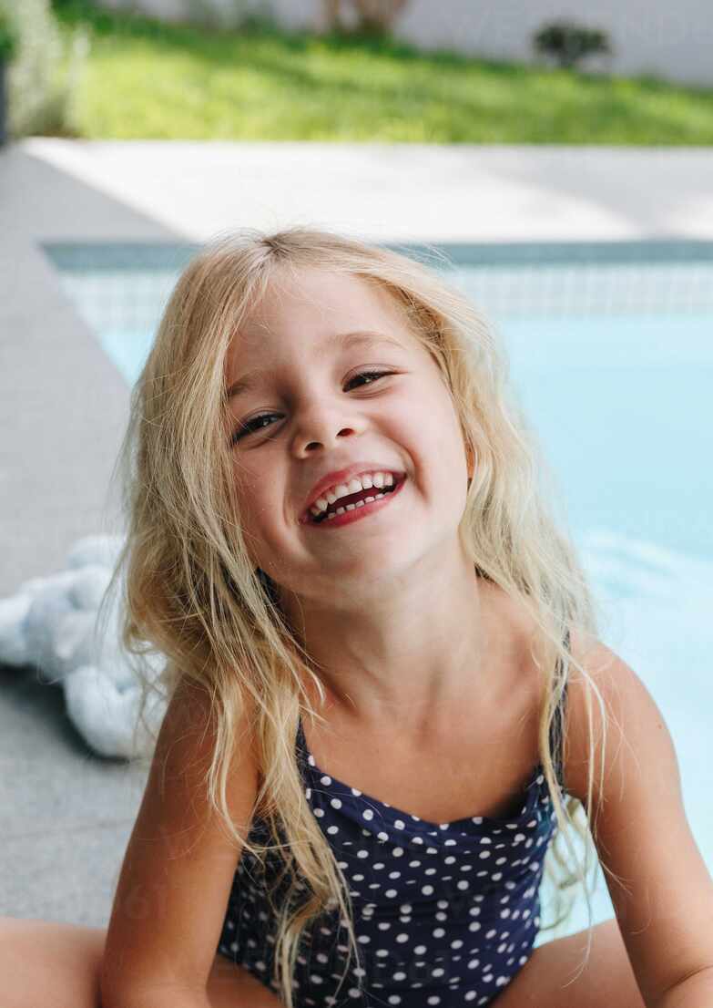 Happy little girl sitting by swimming pool ISF22917