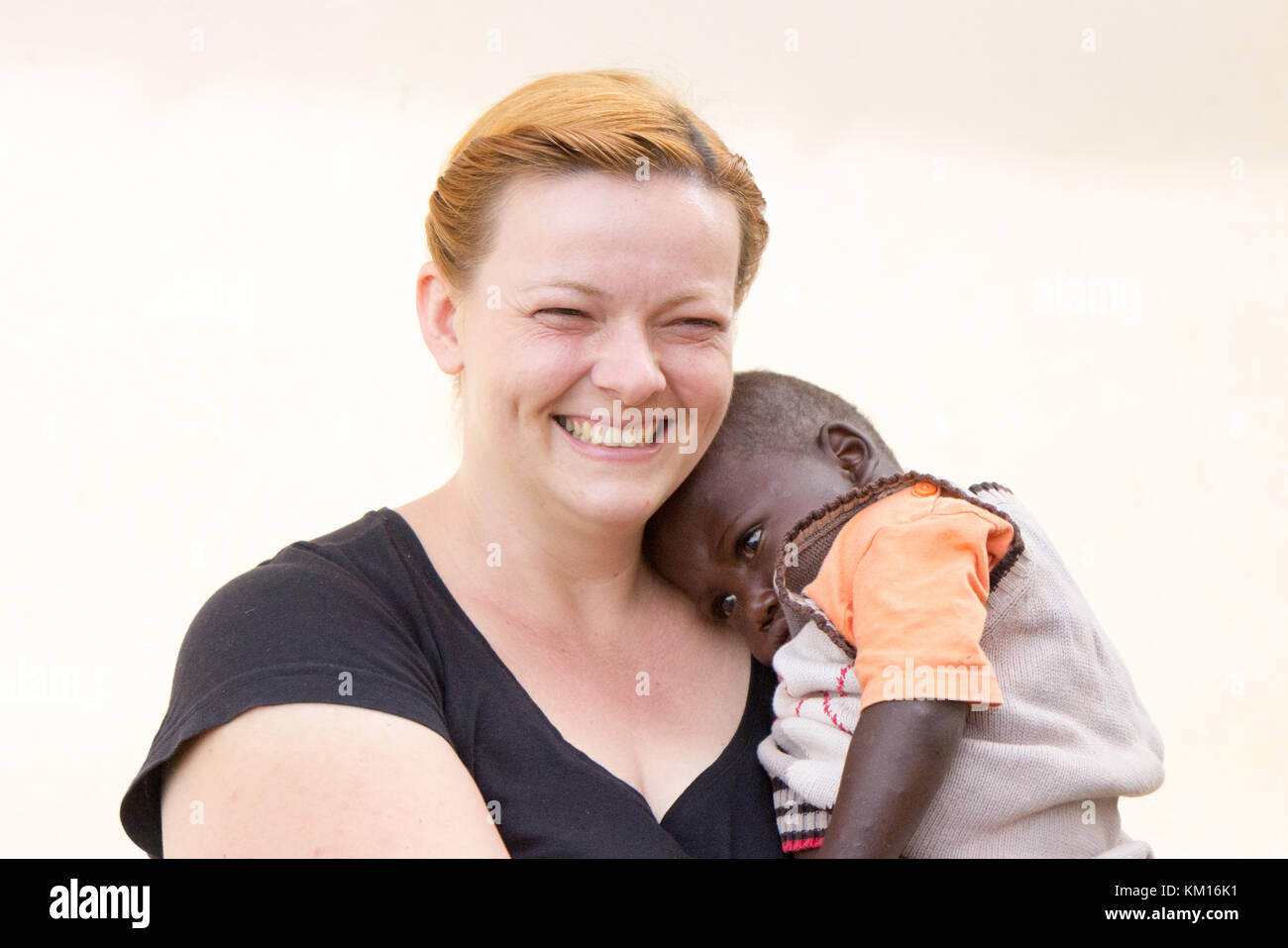 A happy white woman a missionary holding an african boy KM16K1
