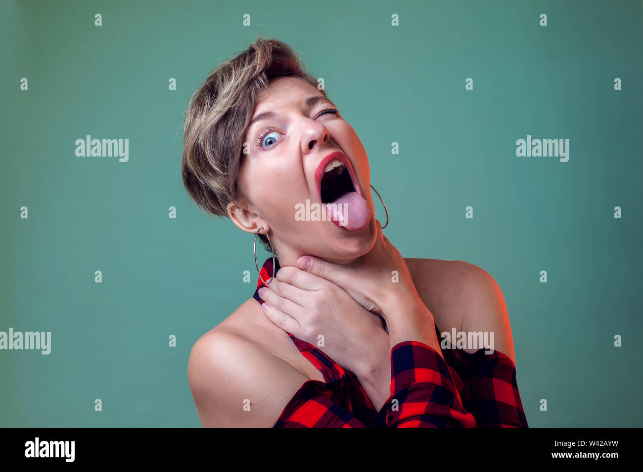 People and emotions a portrait of young woman with short hair choking herself for fun holds ha