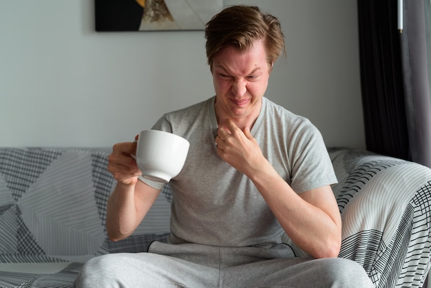 Stressed young man drinking coffee looking disgusted home 251136 30979