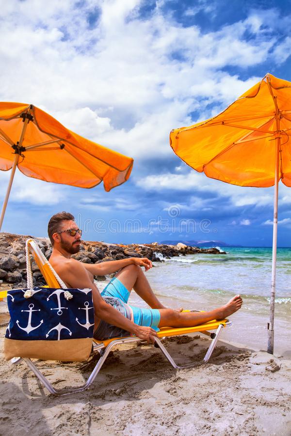 Man relax beach chair sunbathing under yellow umbrella greece crete heraklion 126965574