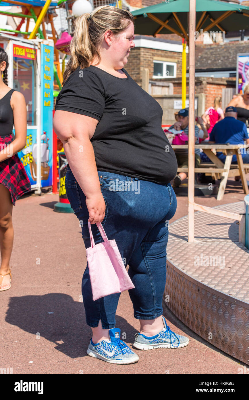 An overweight woman standing beside a ride at a fairground holding HR9G83 An overweight woman standing beside a ride at a fairground holding HR9G83