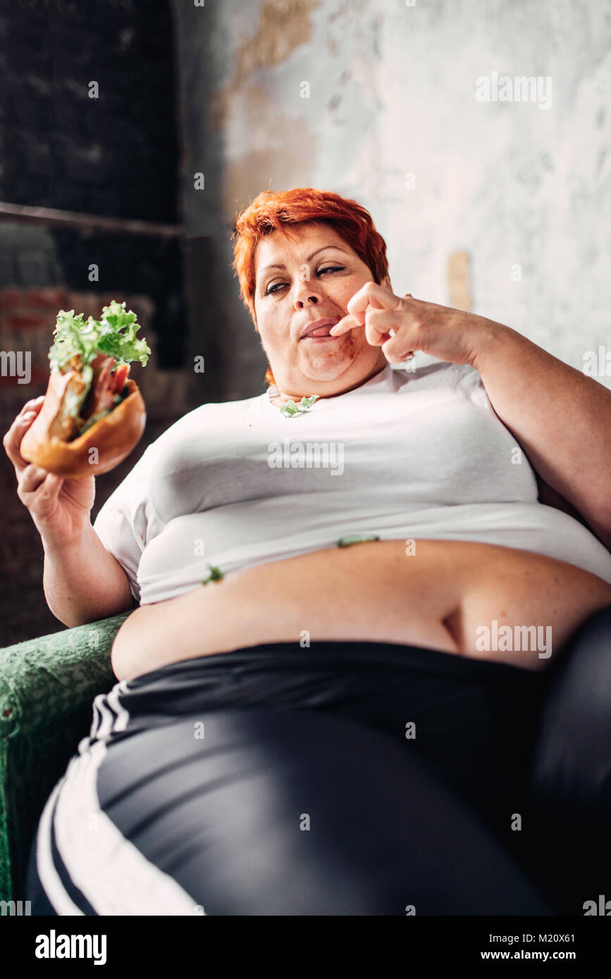 Fat woman sits in a chair and eats sandwich overweight fatty and bulimic M20X61