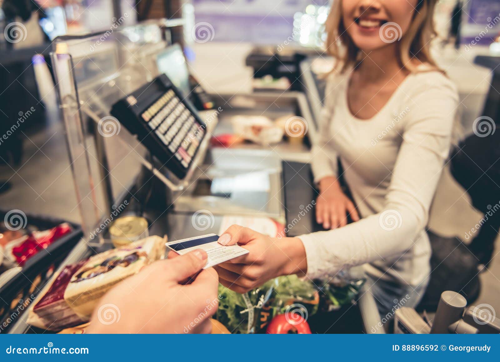 Supermarket cash desk beautiful young cashier holding credit card smiling working 88896592