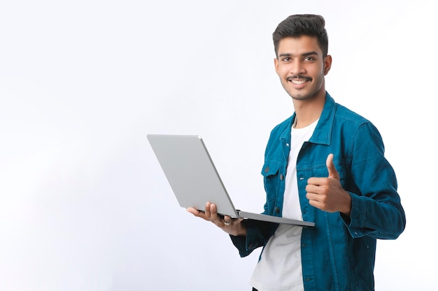 Young indian man using laptop showing thumps up white background 54391 6146