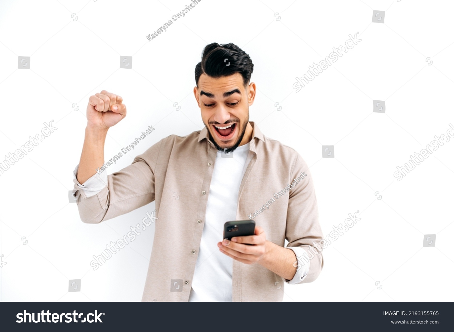 Stock photo win victory triumph joyful amazed excited indian or arabian young man use his smar