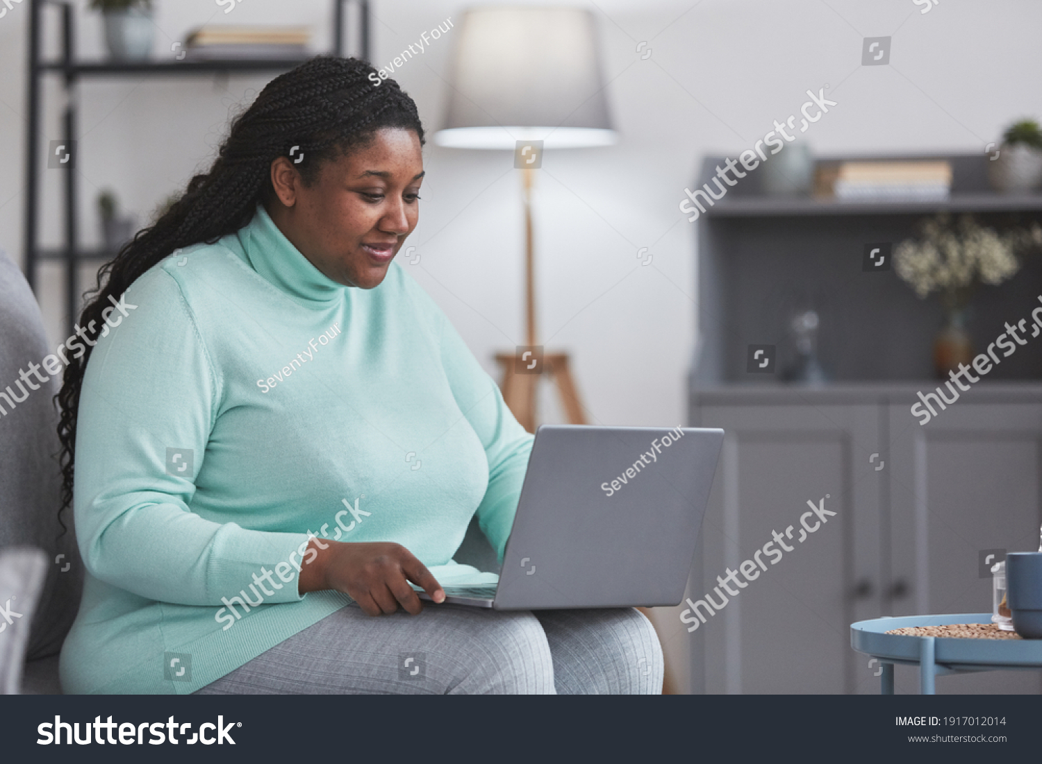 Stock photo portrait of curvy african american woman using laptop and smiling while enjoying w