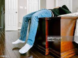 Exhausted Man Rests At Foot Of Bed With Legs Dangling Over Trunk High-Res  Stock Photo - Getty Images