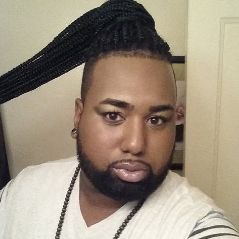 A picture of a gay black male with a ponybun hairstyle for his long hair