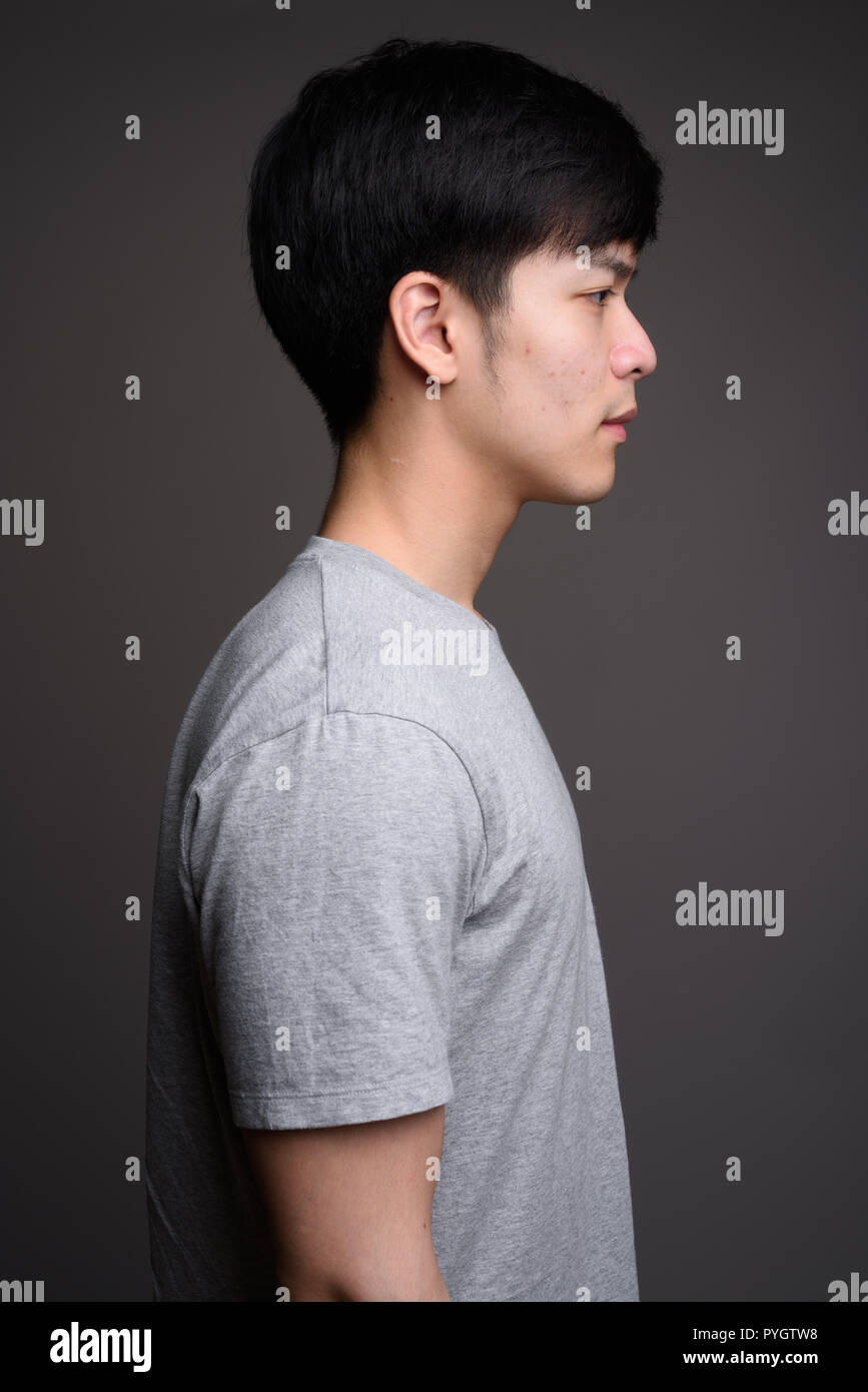 Profile view of young handsome asian man against gray background PYGTW8