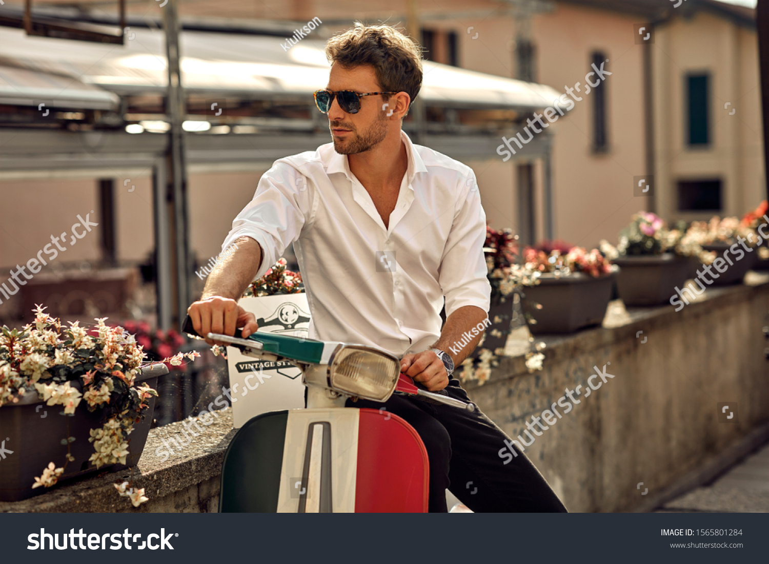 Stock photo stylish italian man wearing white shirt and sitting on classic scooter 1565801284