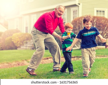 Grandfather playing chasing grandsons outside 260nw 1631756365